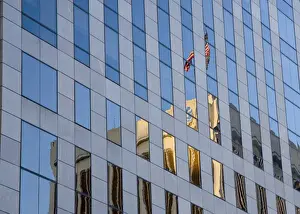 New Orleans Prints: USA, Louisiana, New Orleans. American flag atop building reflected in glass of a skyscraper