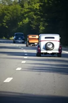 USA, Maine. Three antique cars traveling on a modern highway