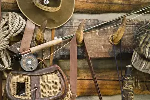 Hook Prints: USA, Montana. Fishing ger and hat hang on horn pegs outside of log cabin