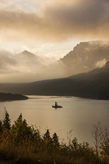 Images Dated 7th August 2013: USA, Montana, Glacier National Park. Sunrise pierces clouds over St. Mary Lake. Credit as