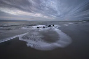 USA, New Jersey, Cape May National Seashore. Pier stumps on cloudy seashore sunrise