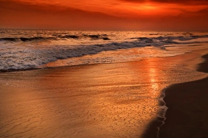 USA, New Jersey, Cape May. Sunset reflections off clouds and ocean shore. Credit as
