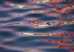USA, New Mexico, Socorro. Bridge reflections create abstract swirling red patterns in water