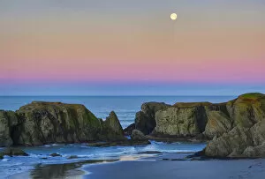 USA, Oregon, Bandon. Full moon sets over sea stacks on beach