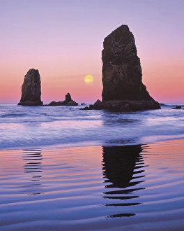 Monolith Prints: USA, Oregon, Cannon Beach. The Needles rock monoliths at sunrise showing moon at moonset