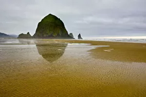 USA, Oregon, Cannon Beach. Sunrise reflection of Haystack Rock at low tide. Credit as