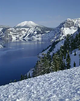 USA, Oregon, Crater Lake National Park. Evening light warms snowy rim of Crater Lake