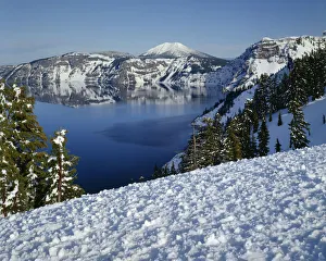 USA, Oregon, Crater Lake National Park. Evening light warms snowy rim of Crater Lake