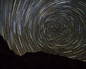 Usa, Oregon, Deschutes River. Circular star trails above cliff
