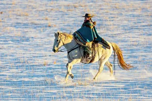 USA, Shell, Wyoming. Hideout Ranch cowgirl riding her horse in the snow. (PR, MR)