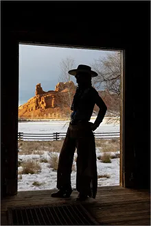 Images Dated 9th June 2022: USA, Shell, Wyoming. Hideout Ranch with cowgirl silhouetted in doorway of log cabin