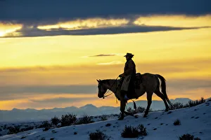Images Dated 9th June 2022: USA, Shell, Wyoming. Hideout Ranch cowgirl silhouetted on horseback at sunset. (PR, MR)