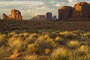 USA, Utah, Monument Valley National Park. Sunrise illumines rock formations and grass on butte