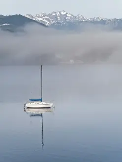 USA, Washington, Seabeck. Sailboat anchored in Hood Canal with Olympic Mountains in background