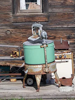 USA, Washington State, Molson, Okanogan County. An old washing machine and old rusty stove on the porch of a building in the historic ghost town