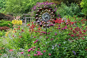 USA, Washington State, Sammamish. Summer perennial flower garden with cone flowers, zinnias. Beebalms, Rebecca. Coleus, Japanese grasses and lawn art, wind wheel