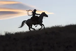 USA, Wyoming, Shell, The Hideout Ranch, Silhouette of Cowgirl with Horse at Sunset