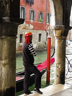 Clothing Prints: Venice, Italy. Gondolier man looks out onto the canal next to his gondola