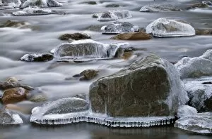 Vermont, USA. Frozen rocks along a river in the winter