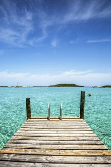Exuma Gallery: Vertical photo with a dock in the foreground, clear water and blue sky in the background