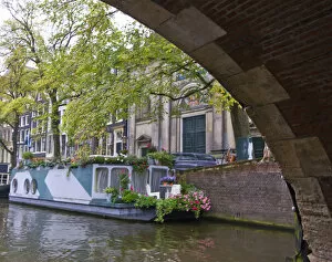 View from under a canal bridge with a colorful houseboat with flowers