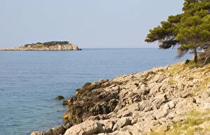 View over coast cliffs with pine trees over the sea water towards an island. Prizba village