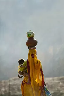 Village woman carrying baby and load on the head, Udaipur, Rajasthan, India