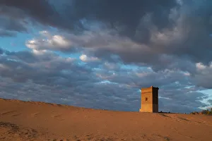 Rissani Prints: Water tower glows orange in sunrise light