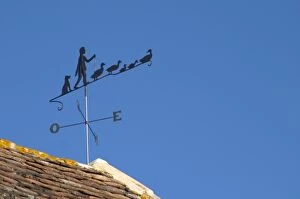 A weathercock weather vane showing a farmer with his or her geese on top of the farm