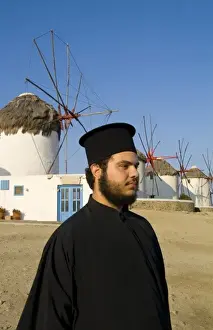 Waist Up Prints: White and blue windmills with a Greek Orthodox priest on the island of Mykonos, Greece