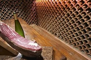 The wine cellar and tasting room, walls are lined with bottles stacked in terracotta