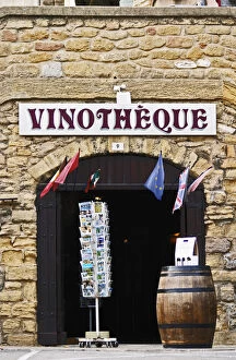 A wine shop vinotheque with flags, post cards on a stand and a barrel with wine bottles