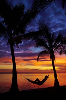 Woman in hammock, and palm trees at sunset, Coral Coast, Viti Levu, Fiji, South Pacific