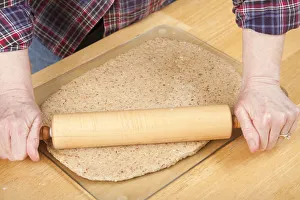 Rolling Prints: Woman rolling ball of bread dough with a rolling pin to flatten it, prior to forming