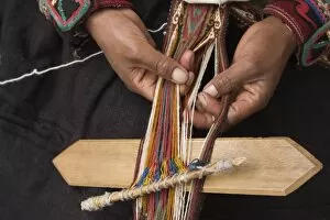 Woman in traditional dress weaving using a backstrap loom (close-up of hands), Chinchero