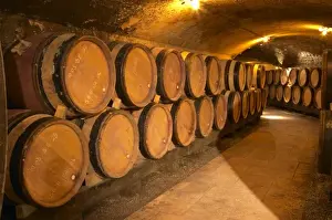Mature Prints: Wooden barrels with aging wine in an underground corridor in the cellar of Guigal in Ampuis