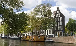 A wooden houseboat with lots o fplants on Prinsengracht Canal