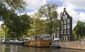 A wooden houseboat with lots o fplants on Prinsengracht Canal A wooden houseboat with lots o fplants on Prinsengracht Canal