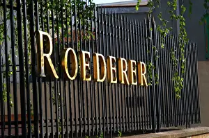 Golden Prints: Wrought iron fence with golden letters shining in the setting sun at Champagne Louis Roederer