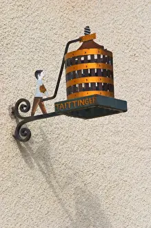 A wrouight iron painted sign that illustrates the theme of champagne and wine production