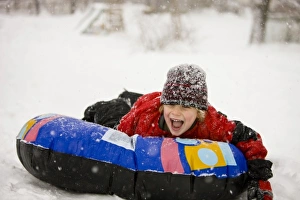 Jerry Marcy Monkman Prints: A young boy sledding on a snow tube during a snowstorm in Portsmouth, New Hampshire